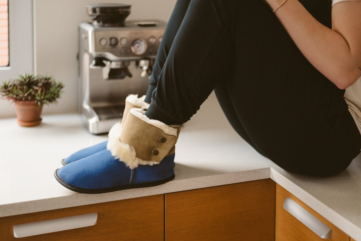 Femme portant des bottillons en mouton renversé marine sur le comptoir de la cuisine. 
